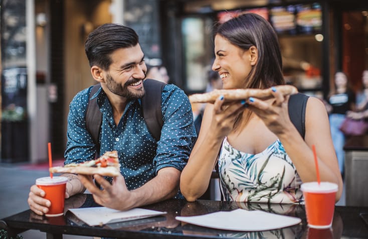 Young couple, eating pizza at the city