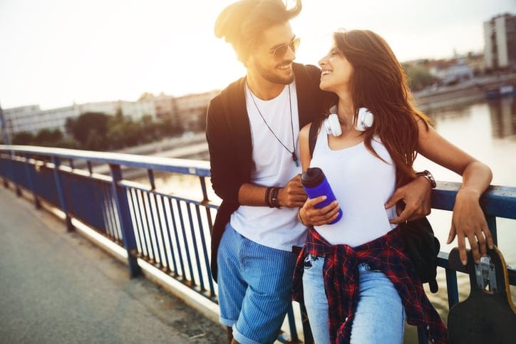 Picture of young attractive couple carrying skateboards