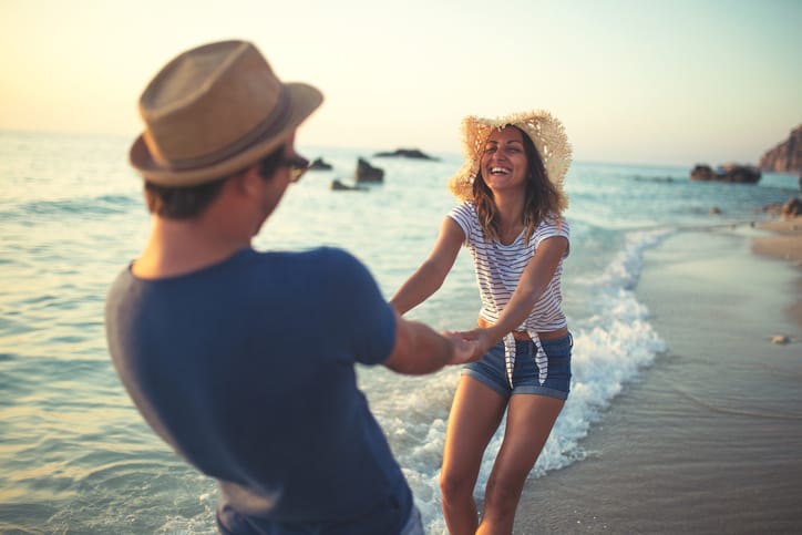 Young couple having fun at the beach in sunset