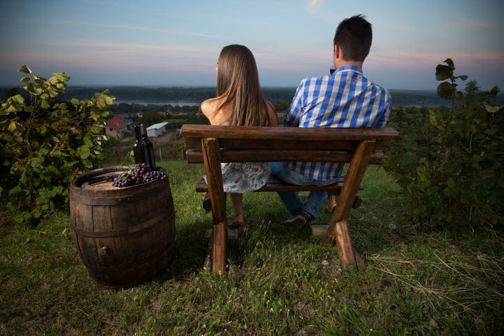Beautiful couple sitting on a bench in vineyard