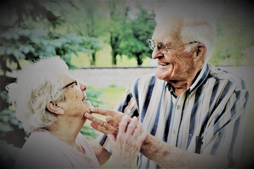 Older couple smiling to one another.