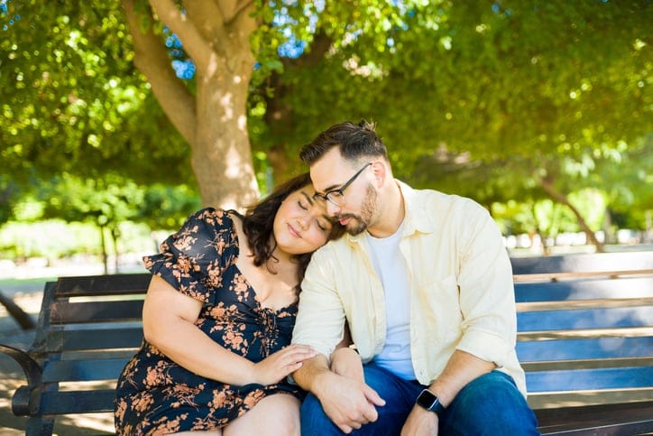 Couple sharing quiet romantic moment on park bench.