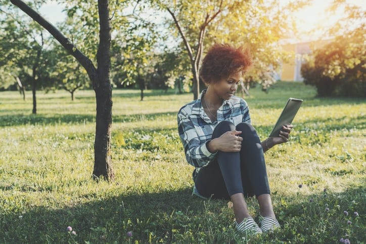 Mixed girl with digital tablet in park