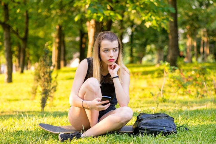 blonde woman sitting outside with smartphone