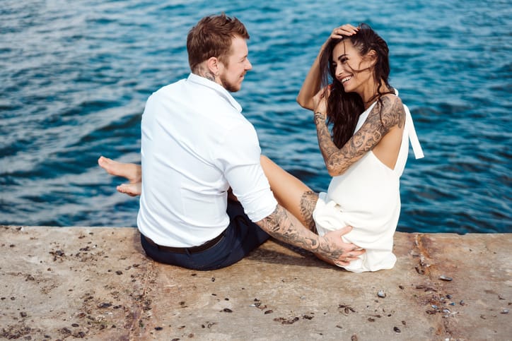 The guy and the girl are sitting on the pier by the sea