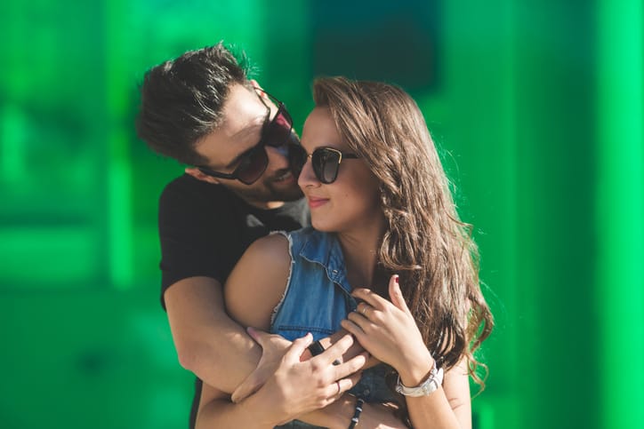 Portrait of young couple in sunglasses cuddling together