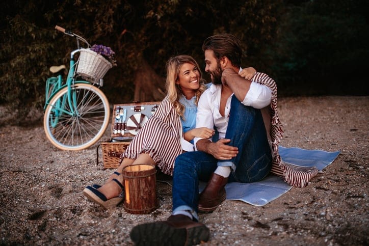Couple in love covered in blanket enjoying picnic time together.