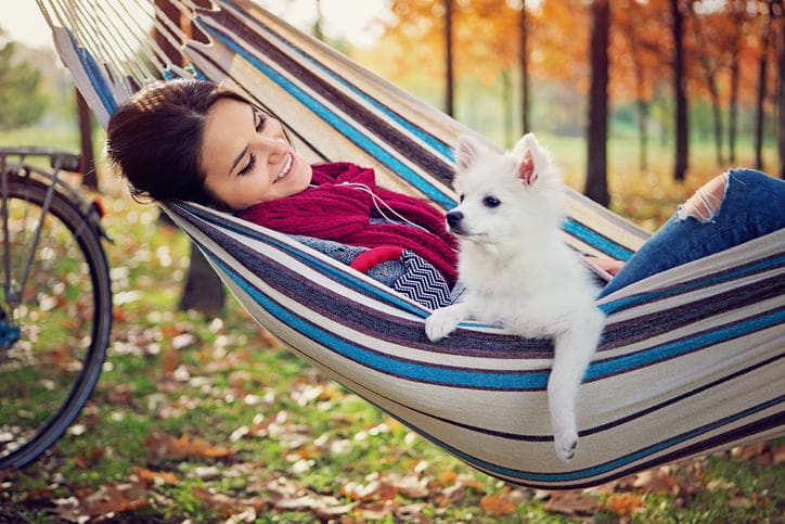 Woman and her little dog in a hammock and listening the music.