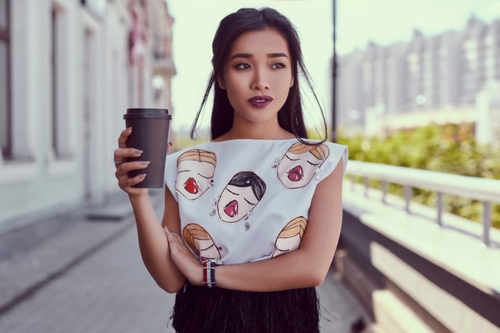 Gorgeous asian woman in fashion dress walking along bright street