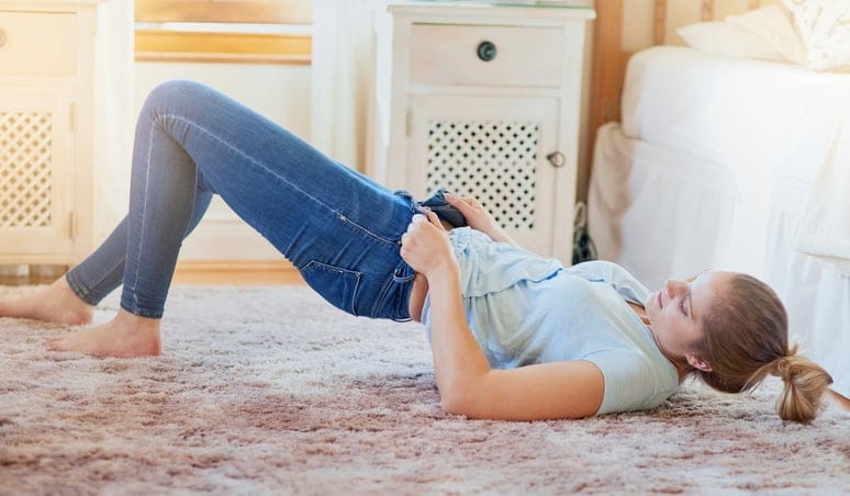 Woman putting skinny jeans on.