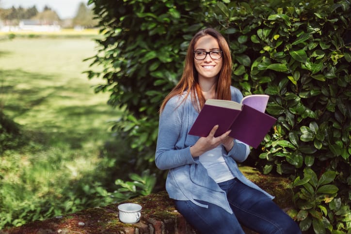 Woman drinking tea and reading a book at the veranda