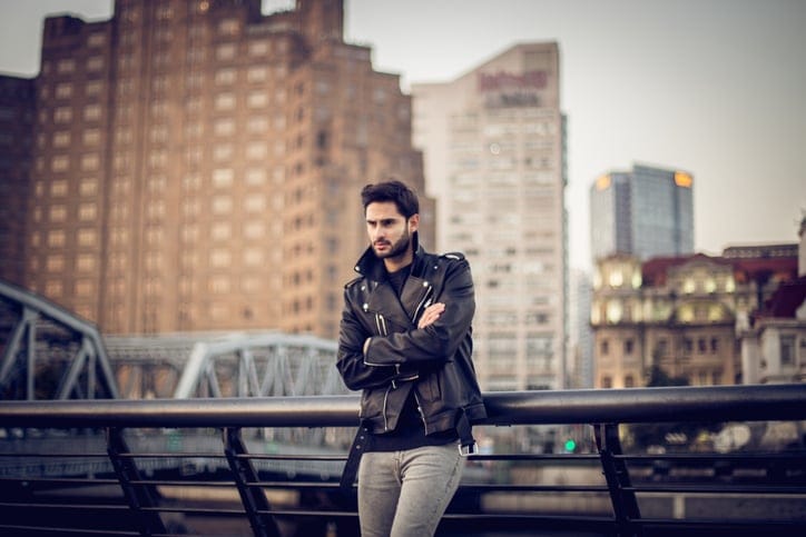 One man, standing on the street alone, arms crossed
