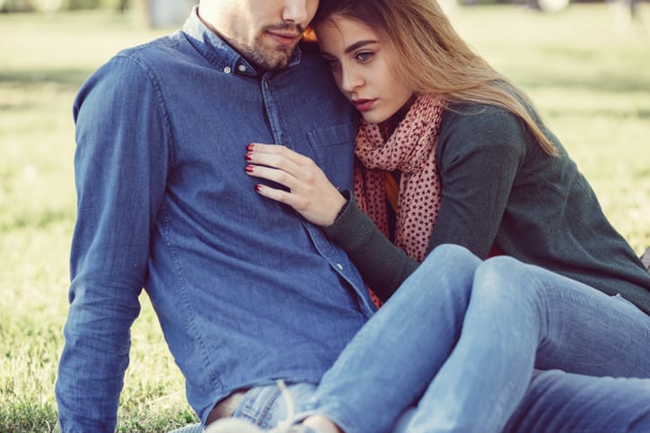 couple hugging sat on the grass
