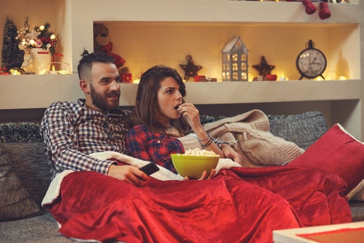 Couple at home eating pop corns while watching movie on tv