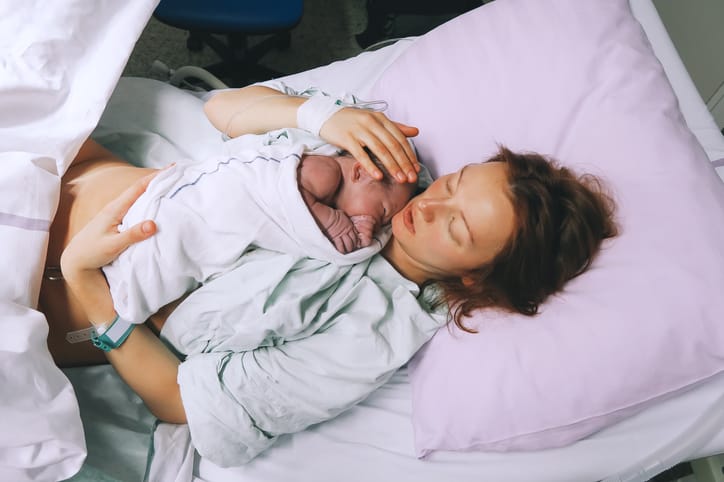 Mother holding her newborn baby child after labor in a hospital.