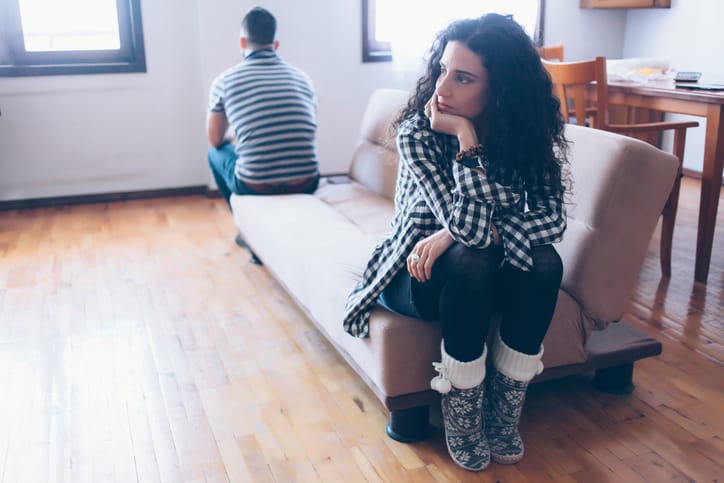 Couple sitting on sofa at home, having relationship problems.