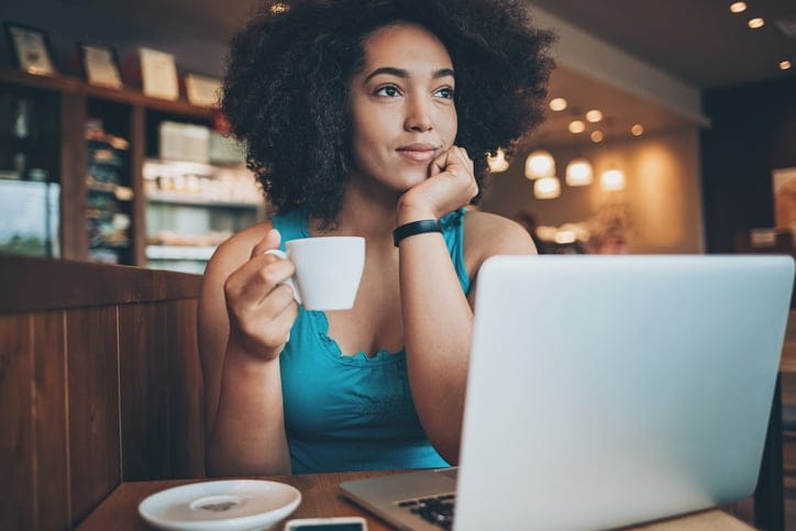 Young woman with laptop drinking coffee in a restaurant