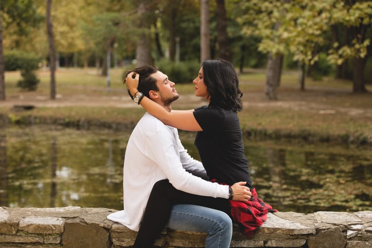 couple sitting wall near river