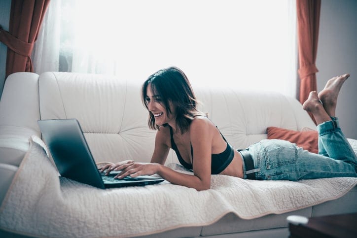 woman laying on couch on laptop
