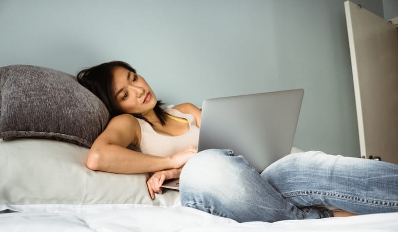 girl laid in bed with laptop