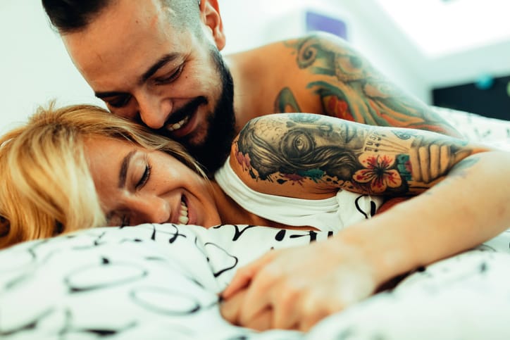couple with tattoos in bed