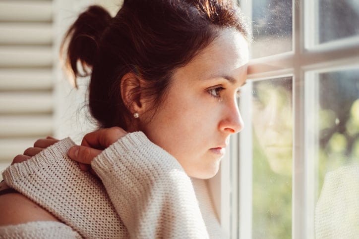 Woman alone looking ot the window.