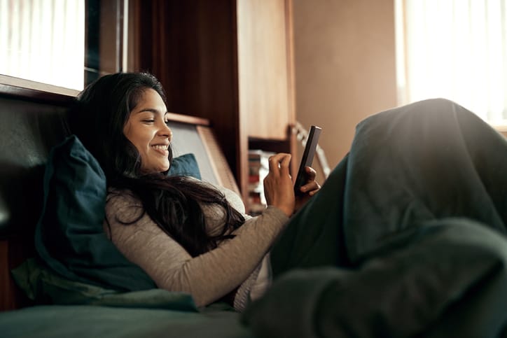 woman in bed texting and smiling