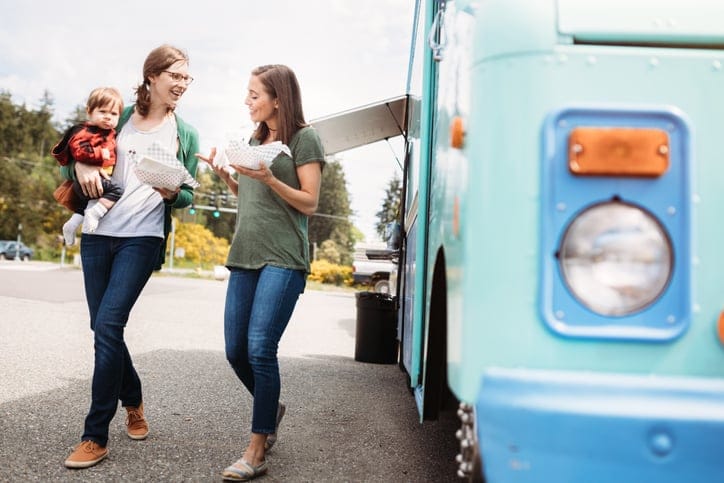 two women standing beside a van