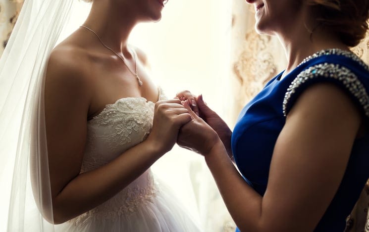 Bride on wedding day holding her mother's hands. Concept of relationship between moms and daughters