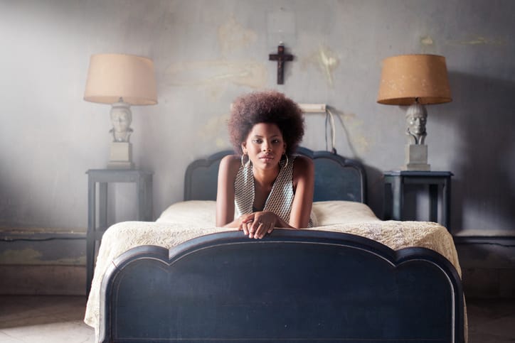 Portrait of confident woman lying on bed at home