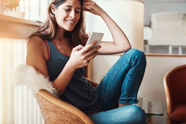 Shot of an attractive young woman using her cellphone at home