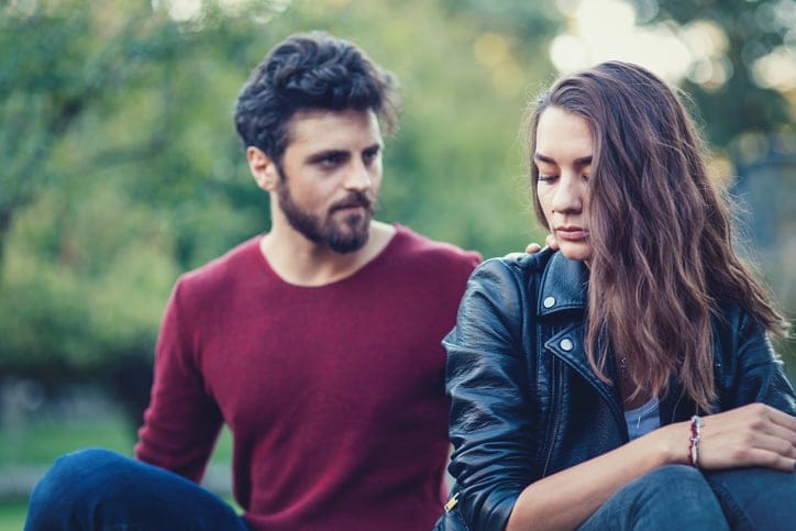 Sad beautiful woman sitting distant from her boyfriend