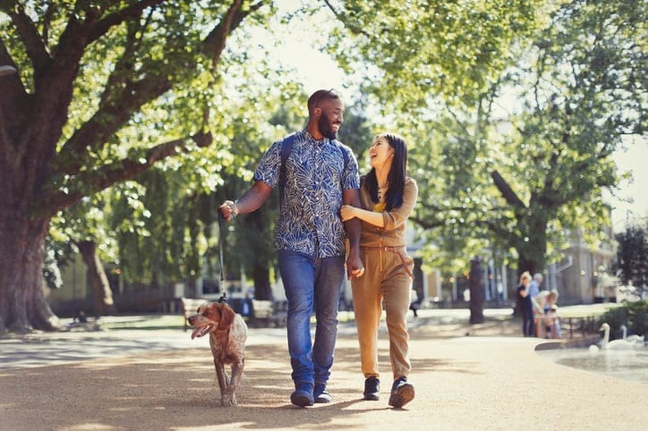 Couple taking their dog for a walk in the park.