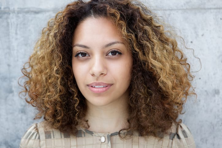 Young woman posing against wall outdoors
