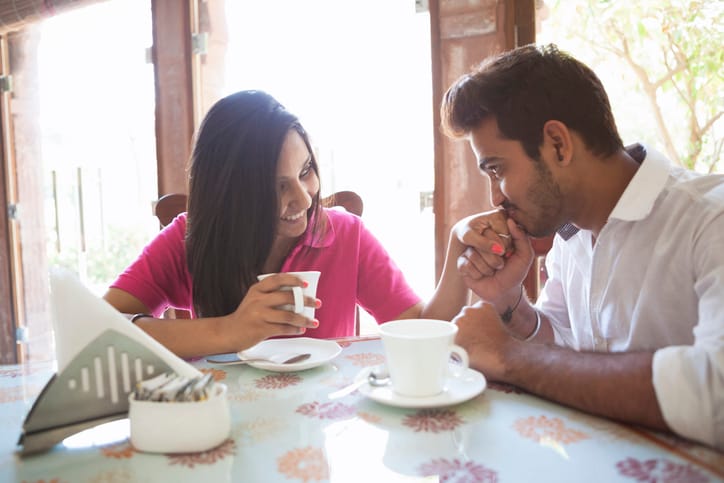 guy kissing girl's hand in cafe