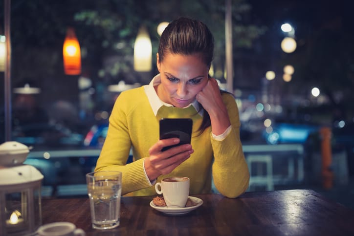 Young woman in a cafe using mobile phone. Shallow DOF