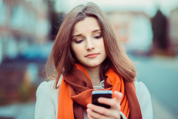 Bad comment on social media. Portrait of a woman walking in the city with cell phone