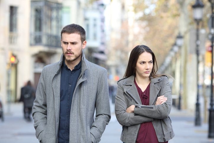 Angry couple walking in the street after argument.