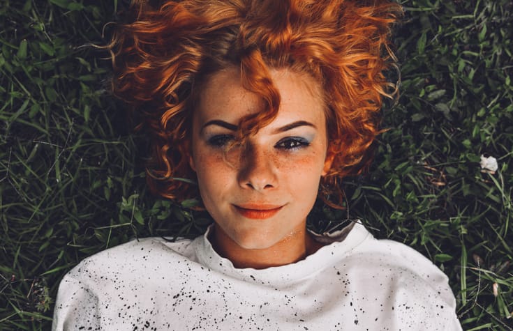 Beautiful young woman lying down in the grass