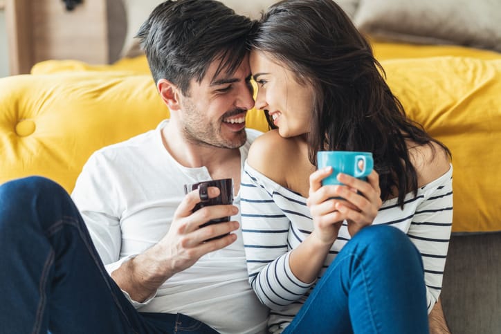 Happy young couple drinking coffee at home spending time together