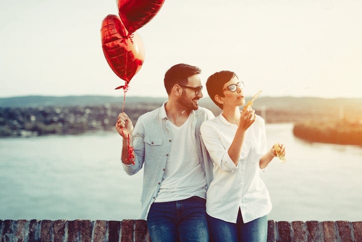 Couple in love dating and holding red baloons hearts on valentine day