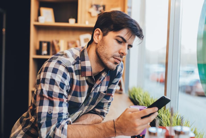man texting at a cafe