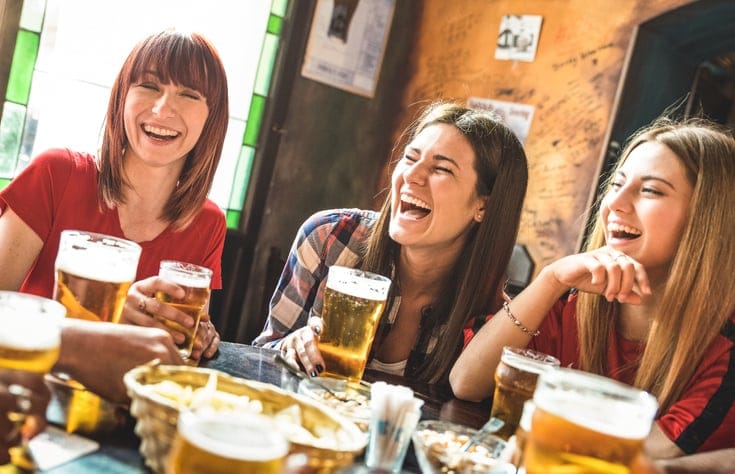 Happy girlfriends drinking beer at brewery.