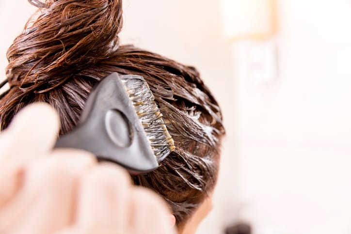 Woman dying her hair in front of mirror.