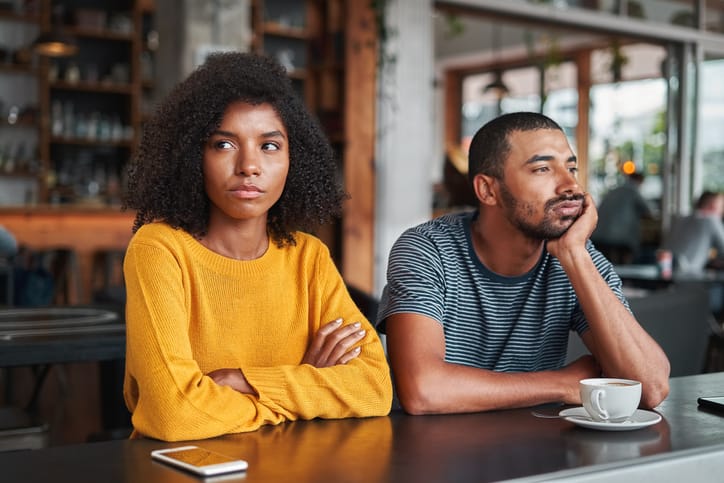 Sad and angry young couple in cafe.