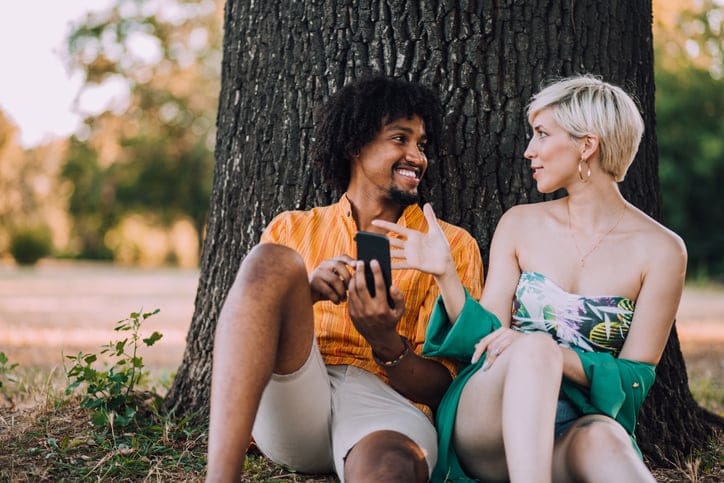 mixed race couple sitting by a tree