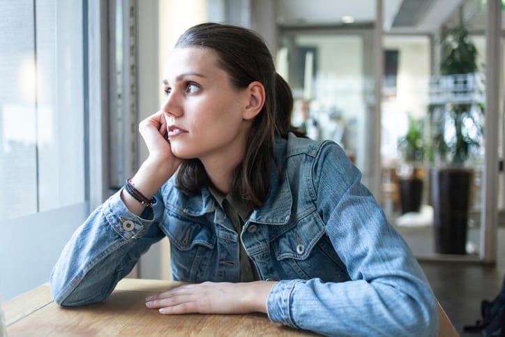 woman in denim looking out of the window