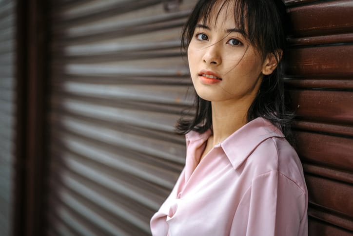 asian lady standing beside a wall