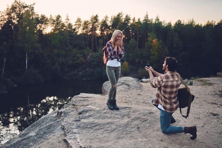 man on bended knee proposing to woman