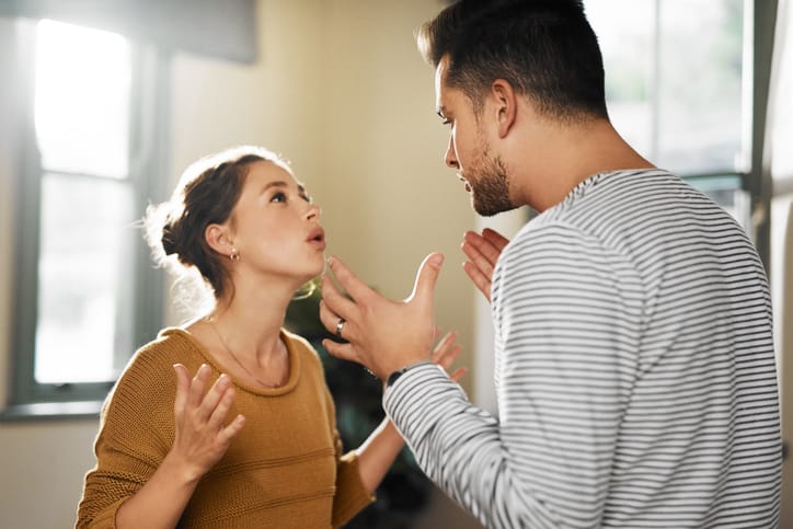couple arguing and holding hands up